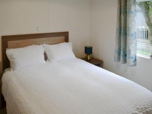 a white bed with white pillows and a window at Ocean Glade - Uk32963 in Corton
