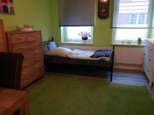 a bedroom with a bed and a dresser and two windows at Wahlmann bed &breakfast in Hannover