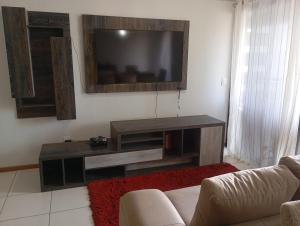 a living room with a couch and a television on the wall at Apartment 3 suites cop30 in Belém