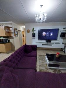a living room with a purple couch and a tv at Lubsman Apartments in Centurion