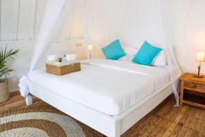 a bedroom with a white bed with blue pillows at Cleosa 2 BR Cozy Bungalow Family ZN301 in Gili Air
