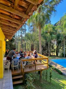 eine Gruppe von Menschen, die an einem Tisch unter einer Pergola sitzen in der Unterkunft Nature and Comfort House with Pool 10 people 1h from SP in São Roque