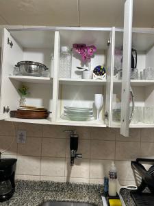 a kitchen cabinet with plates and dishes in it at Nosso Sonho Praia Seca in Araruama +76 photos