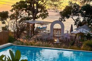 a swimming pool with a table and chairs and the ocean at Cleosa 2 BR Cozy Bungalow Family ZN301 in Gili Air