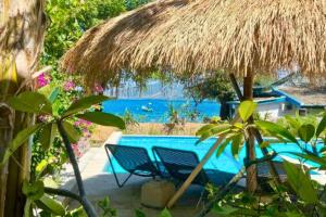 a swimming pool with two chairs and a straw umbrella at Cleosa 2 BR Cozy Bungalow Family ZN301 in Gili Air