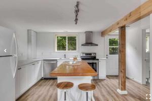 a white kitchen with a wooden table in it at Le Nørda sur la rivière Vallée Bras du Nord in Saint-Raymond