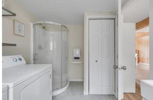 a white bathroom with a shower and a washing machine at Le Nørda sur la rivière Vallée Bras du Nord in Saint-Raymond