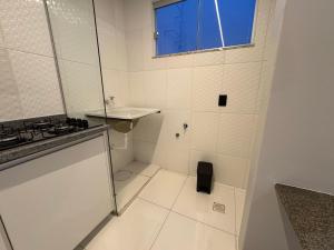 a small white bathroom with a sink and a window at Apartamento no centro! Próximo a tudo! in Barreiras
