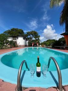 a bottle of wine and glasses in a swimming pool at Apartamento, piscina, natureza e sossego in Macapá