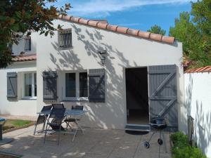 a small white house with a table and chairs at Charmante maison au calme près de la plage, jardinet privatif, 4 pers, animaux sur demande - FR-1-476-13 in La Faute-sur-Mer +2 photos