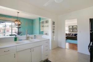a white kitchen with a sink and a living room at West Beach Villa 2 in Santa Barbara +33 photos
