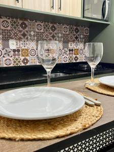 two wine glasses and a plate on a kitchen counter at ApComplete in the center in Caxias do Sul