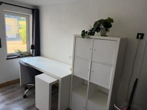 un bureau blanc et une armoire avec une plante en pot dans l'établissement Ferienwohnung Lappano - Losheim am See, à Bachem