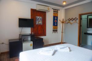 Un dormitorio con una cama blanca y un televisor. en Villa Namkhan River, en Luang Prabang