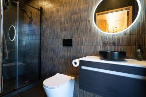a bathroom with a toilet and a sink and a mirror at Foudre Suite with Hot Tub at Barrelled Wines Raglan in Raglan +31 photos