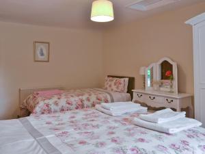 a bedroom with two beds and a mirror and towels at Bellegrove Cottage in Watermillock