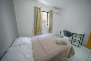 a bedroom with a bed with a desk and a window at Casa Queiroz in Porto De Galinhas