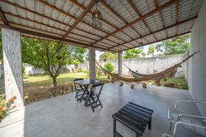 a porch with a hammock and a table and chairs at Casa Queiroz in Porto De Galinhas