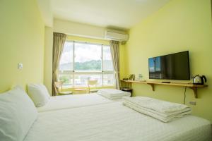 a hotel room with two beds and a flat screen tv at Siang Jhan B&B in Taitung City