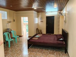 a bedroom with a bed and two green chairs at Tenstay Homes & Independent Villa in Virāmpattinam