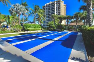 a blue tennis court with palm trees and a building at The Wave Song in Fort Pierce