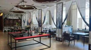 a dining room with tables and chairs and windows at Xian Empress Hotel in Xi'an