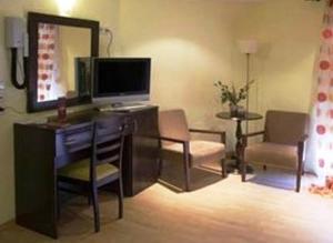 a living room with a desk with a television and a mirror at Kornilios Istron Hotel in Giannitsa