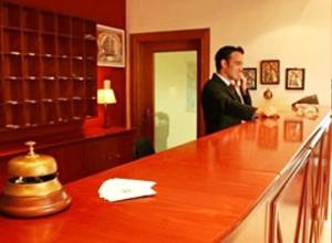 a man in a suit standing behind a bar at Kornilios Istron Hotel in Giannitsa