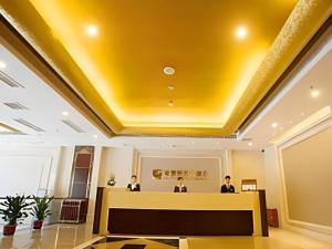 a lobby with three people in a yellow ceiling at Wuhan Yamao Hengsheng Hotel in Wuhan