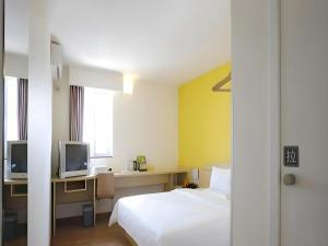 a hotel room with a bed and a desk with a tv at 7 Days Inn Luoyang Wangcheng Park Metro Station in Luoyang