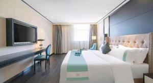 a hotel room with a large bed and a desk at Xana Hotelle Jinan Daminghu North Gate in Jinan
