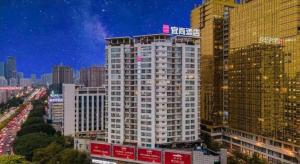 a tall white building with a sign on top of it at Echarm Hotel Nanning the MixC Exhibition Center Metro Station in Nanning