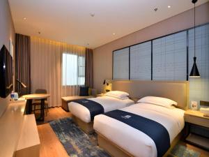 a hotel room with two beds and a desk at Echarm Hotel Xian Ming City Wall South Gate in Xi'an