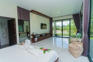 a bedroom with a large bed and a bathroom at Suan Son Villa Koh Sa Nher สวนสนธิ์วิลล่า เกาะเสนอ SHA in Surat Thani