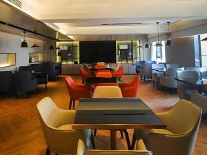 a restaurant with tables and chairs and a flat screen tv at Echarm Hotel Kunming High-speed Railway South Station Chunrong Street Metro Station in Kunming