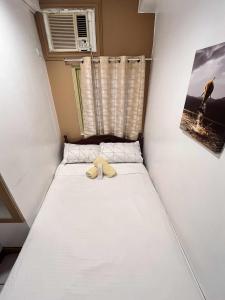 a white bed with a yellow bow tie on it at Ace Travellers Inn- Palawan in Puerto Princesa City