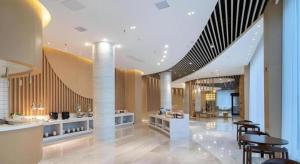 a lobby with tables and chairs in a building at Deep Sleep Hotel Xuzhou High-Speed Railway Station East Square Oubeisha in Xuzhou