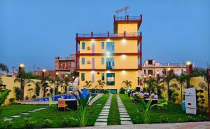 a yellow building with people sitting in front of it at Elite Stay Hotel and Resort in Bāwal