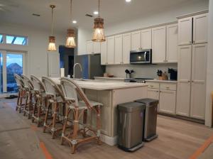 a kitchen with white cabinets and a counter with chairs at Sea'scape - Heated Pool, Beach Gear, Pet Friendly, Beach Views in Pensacola Beach
