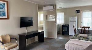 ein Zimmer mit einem Schreibtisch mit Fernseher und einem Bett in der Unterkunft Takanini Park Motor Lodge in Auckland