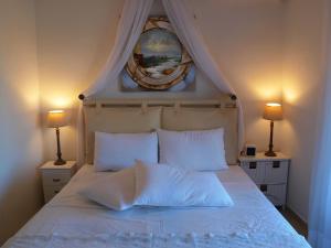 a white bed with two lamps and a picture on the wall at Melograno in Kala Nera