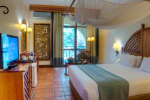 a bedroom with a large bed and a television at Victoria Falls Rainbow Hotel in Victoria Falls