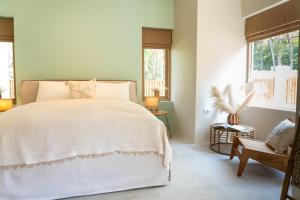 een slaapkamer met een wit bed en een stoel bij The Palm Villa in Ban Ai Dao +67 foto's