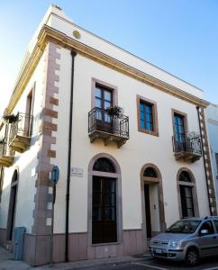 Un bâtiment blanc avec une voiture garée devant. dans l'établissement B&B Il Porticciolo Portoscuso, à Portoscuso