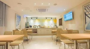 a restaurant with tables and chairs and a kitchen at City Comfort Inn Wuhan Huanghe Tower Shouyi Metro Station in Wuhan