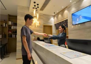 two men shaking hands at a counter in a store at City Comfort Inn Wuhan Optics Valley OuYada Yangjiawan Metro Station in Wuhan