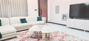 a living room with two white couches and a tv at EkDatta-Irving in Ajman 
