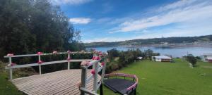 a wooden deck with pink roses on it next to a lake at Cabaña donde Chapalla in Queilén