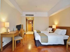 a hotel room with two beds and a desk at Caritas Oswald Cheung International House in Hong Kong