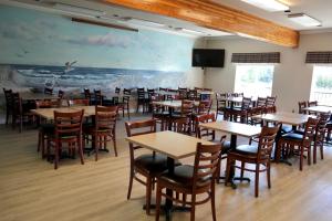 a dining room with tables and chairs and a painting at Coratel Inn and Suites By Jasper Ocean Shores in Ocean Shores